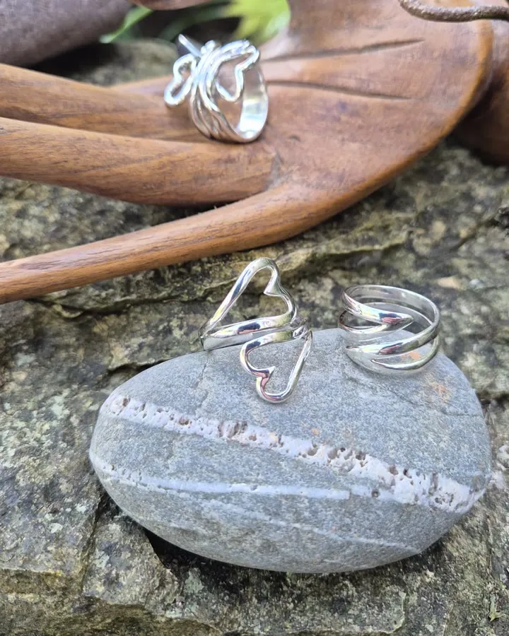 Heart and wrap silver rings on a beach stone