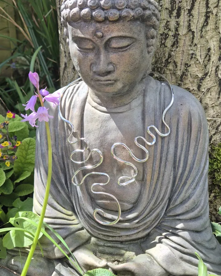 Wave-form silver necklace on a stone figure